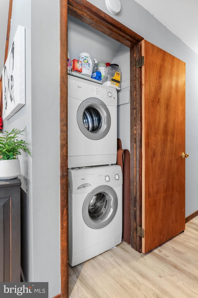 laundry room with stacked washer and dryer, wood finished floors, and laundry area