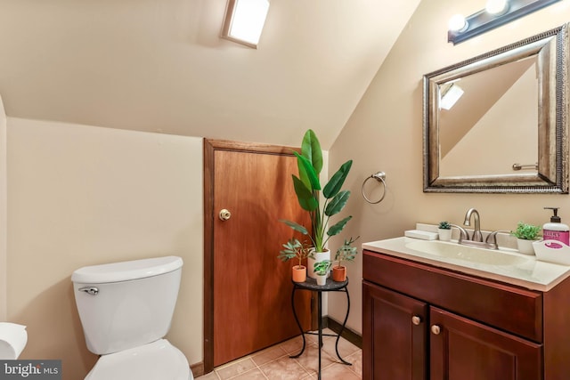 half bathroom with vanity, vaulted ceiling, toilet, and tile patterned flooring