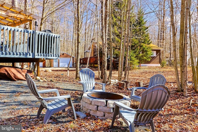 view of patio / terrace featuring a deck, an outdoor structure, and an outdoor fire pit