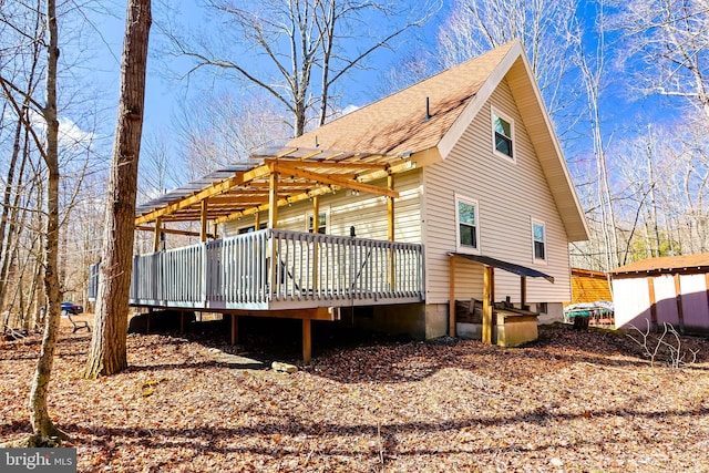 view of side of property with roof with shingles and a deck