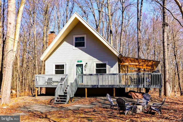 rear view of property featuring a deck, a fire pit, and a chimney