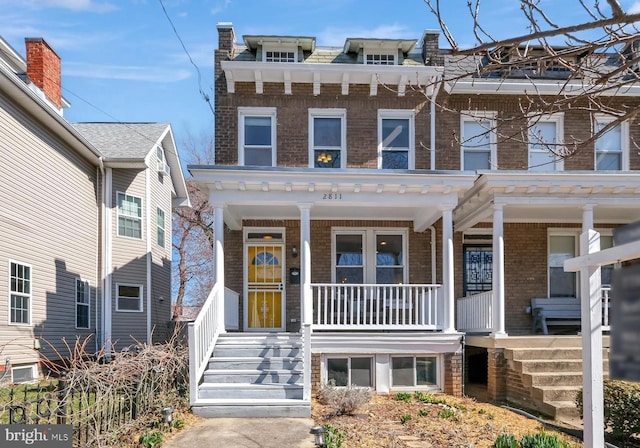 view of front facade featuring brick siding and covered porch