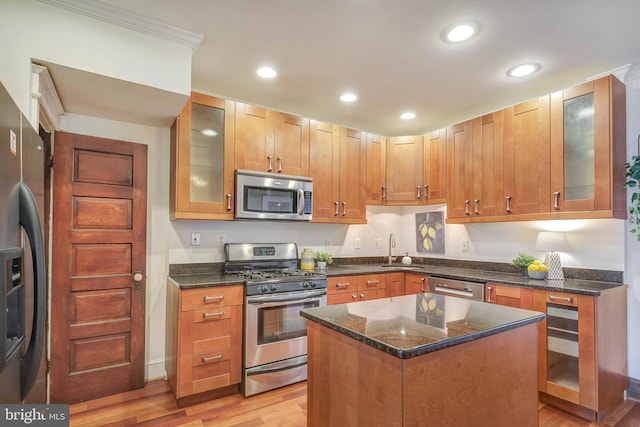 kitchen with dark stone countertops, recessed lighting, a sink, stainless steel appliances, and light wood-style floors