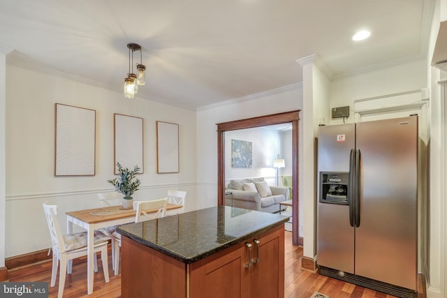 kitchen with dark stone countertops, light wood-style floors, ornamental molding, and stainless steel refrigerator with ice dispenser