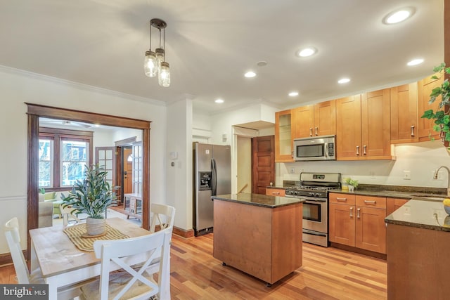 kitchen with a sink, dark stone countertops, a kitchen island, stainless steel appliances, and crown molding