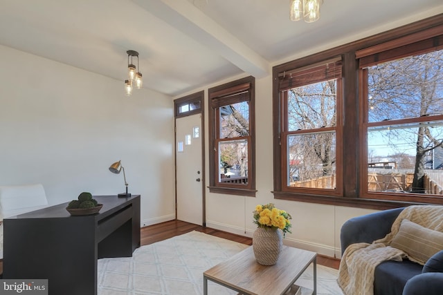 interior space with baseboards, beam ceiling, and wood finished floors