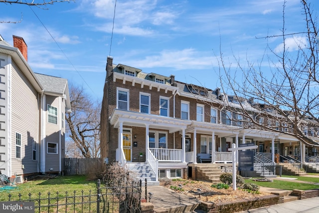 view of front of property featuring brick siding, a porch, and fence