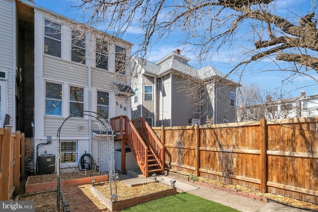 rear view of property with a vegetable garden, central AC, and fence