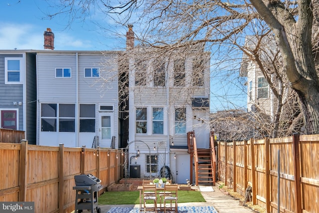 back of property featuring central AC, a fenced backyard, and stairs