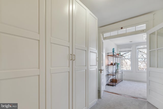 hall with baseboards and light colored carpet