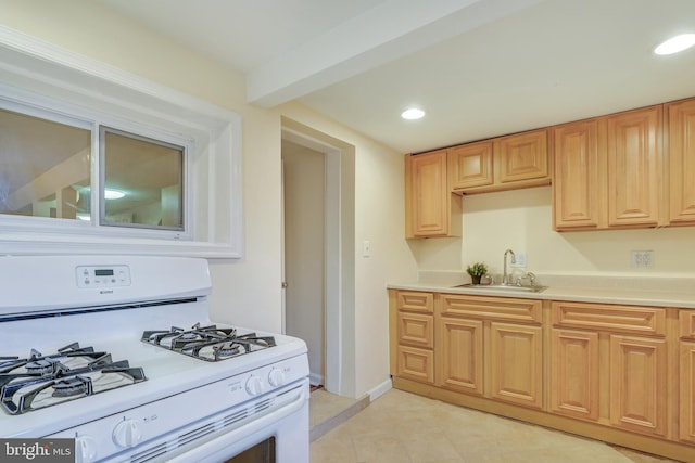 kitchen with white range with gas cooktop, a sink, recessed lighting, light tile patterned flooring, and light countertops