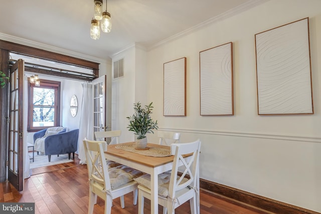 dining room with hardwood / wood-style floors, visible vents, baseboards, and ornamental molding