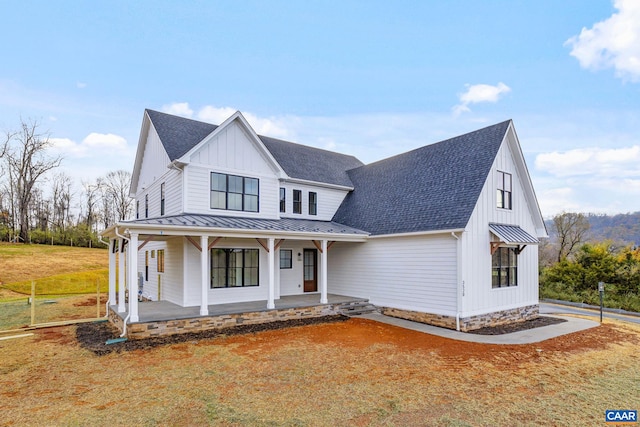 modern farmhouse style home featuring a standing seam roof, covered porch, board and batten siding, a shingled roof, and metal roof