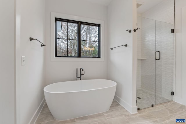 full bath with a shower stall, baseboards, and a freestanding bath