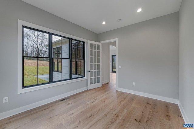 spare room featuring plenty of natural light, baseboards, visible vents, and light wood-type flooring