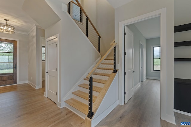 stairs featuring a chandelier, baseboards, and wood finished floors