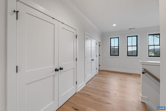 hallway featuring visible vents, ornamental molding, recessed lighting, light wood-style floors, and baseboards