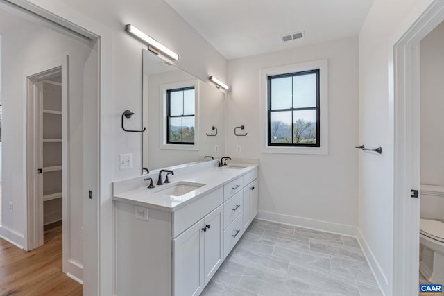 full bath featuring visible vents, a healthy amount of sunlight, toilet, and a sink