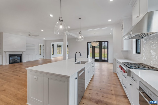 kitchen with a sink, under cabinet range hood, white cabinets, and stainless steel gas cooktop