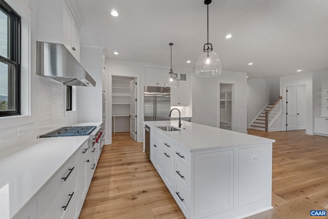 kitchen featuring a sink, recessed lighting, light wood-style floors, and exhaust hood