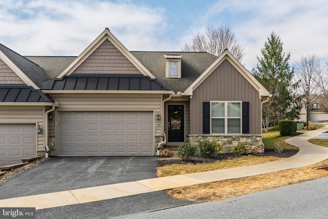 view of front of home with a standing seam roof, aphalt driveway, stone siding, board and batten siding, and a garage