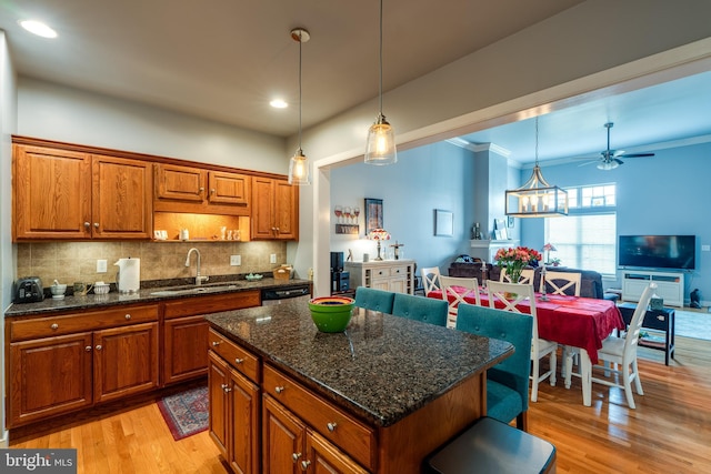 kitchen featuring backsplash, open floor plan, light wood-type flooring, brown cabinetry, and a sink