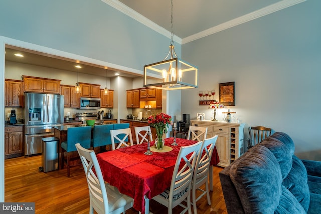 dining space with an inviting chandelier, recessed lighting, ornamental molding, dark wood-type flooring, and a towering ceiling