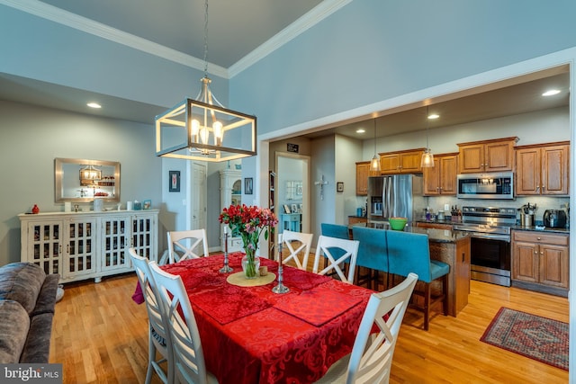 dining room with light wood finished floors, recessed lighting, ornamental molding, a towering ceiling, and a notable chandelier