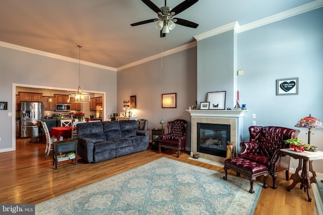 living area featuring wood finished floors, a towering ceiling, and ornamental molding