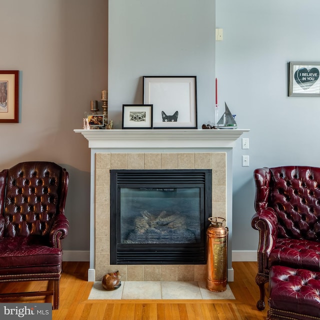 interior details with baseboards, wood finished floors, and a tile fireplace