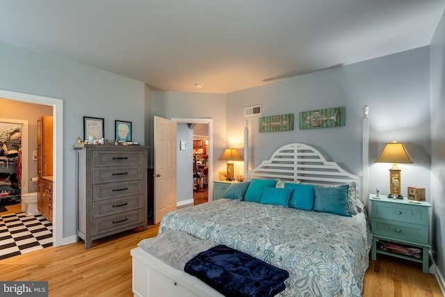 bedroom with a walk in closet, light wood-style flooring, visible vents, and a closet