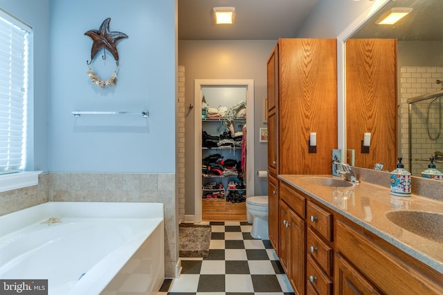 bathroom featuring tile patterned floors, a garden tub, double vanity, and a sink