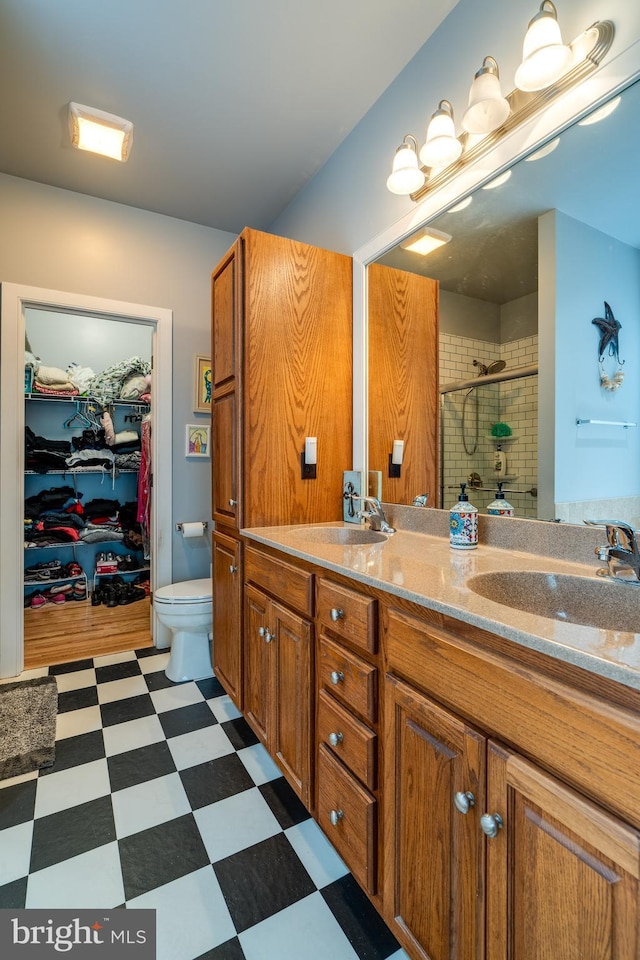 bathroom with a sink, a spacious closet, a shower stall, and tile patterned floors