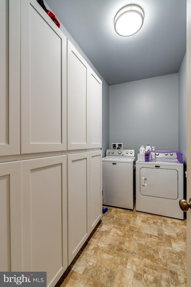 washroom with cabinet space, separate washer and dryer, and stone finish flooring