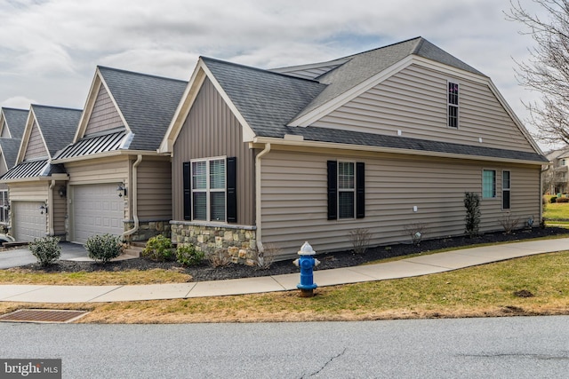 view of property exterior with driveway, stone siding, board and batten siding, a shingled roof, and a garage