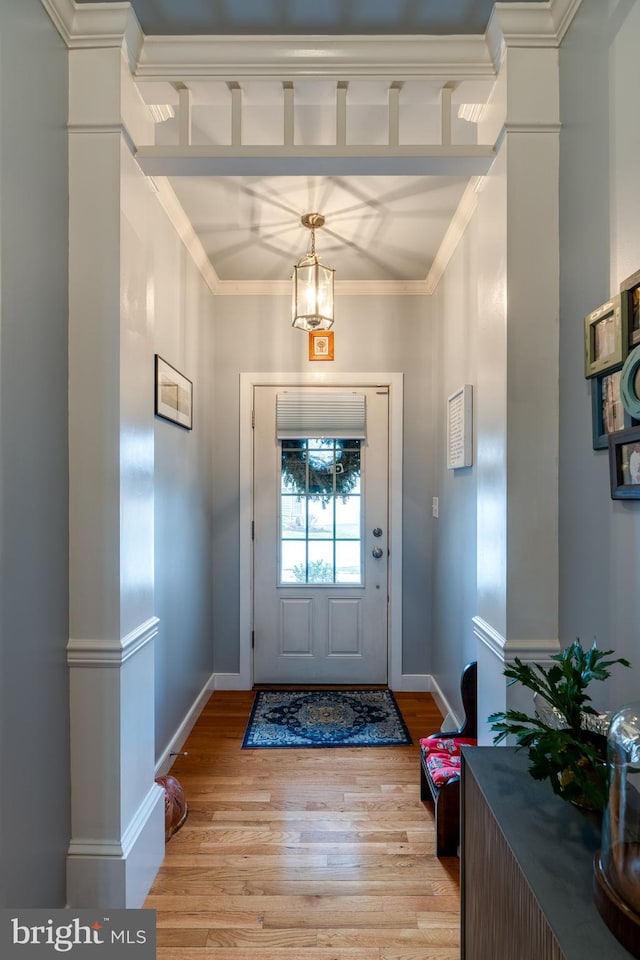 foyer entrance featuring light wood-style flooring, baseboards, and ornamental molding