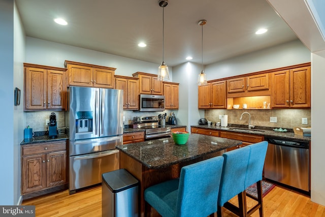 kitchen with a sink, stainless steel appliances, light wood-type flooring, and brown cabinetry