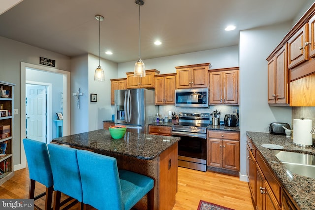 kitchen with stainless steel appliances, light wood-style flooring, and brown cabinetry