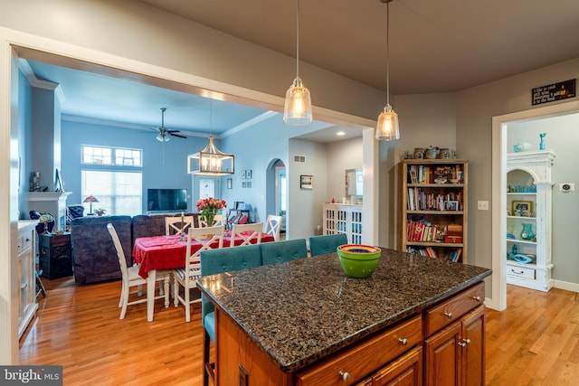 kitchen featuring brown cabinetry, open floor plan, light wood finished floors, and a breakfast bar area