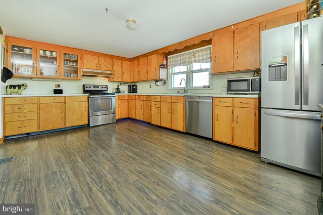 kitchen with under cabinet range hood, dark wood-style floors, appliances with stainless steel finishes, and light countertops