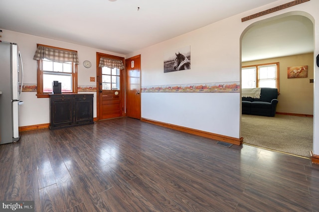 foyer featuring arched walkways, visible vents, baseboards, and dark wood-style flooring