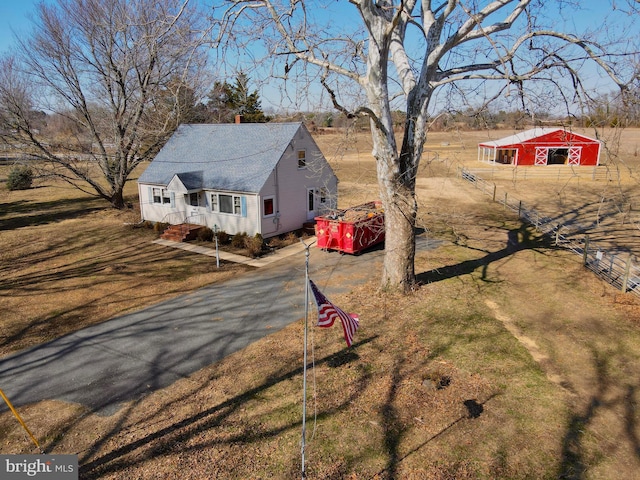 view of front of house featuring an outdoor structure, fence, driveway, and a chimney