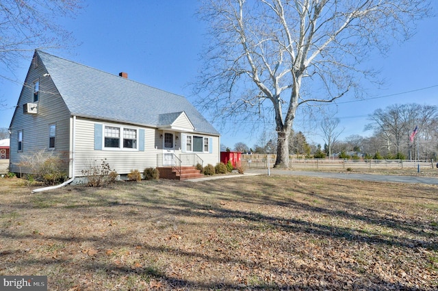 view of front of house with a front yard, roof with shingles, a chimney, and fence