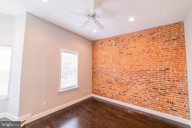 empty room featuring dark wood-type flooring, recessed lighting, brick wall, baseboards, and ceiling fan