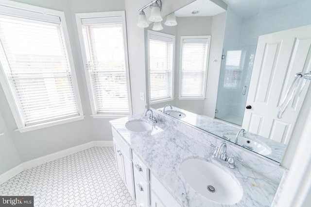 bathroom featuring double vanity, a shower stall, baseboards, and a sink