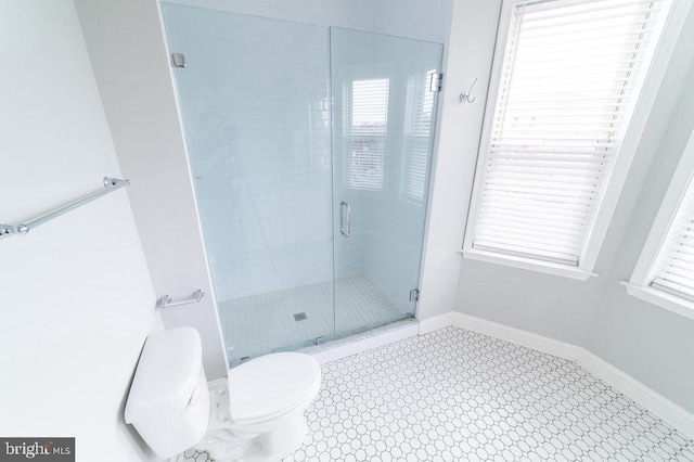 bathroom featuring a stall shower, toilet, and baseboards