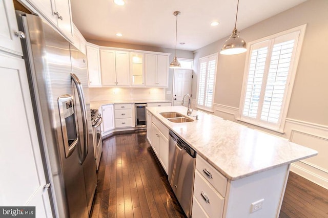 kitchen with beverage cooler, dark wood finished floors, wainscoting, appliances with stainless steel finishes, and a sink