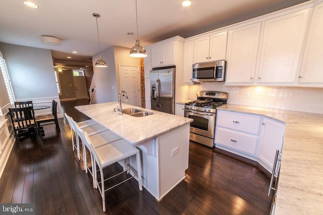 kitchen with a sink, tasteful backsplash, dark wood finished floors, white cabinetry, and stainless steel appliances