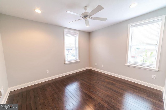 empty room with plenty of natural light, dark wood-type flooring, and baseboards