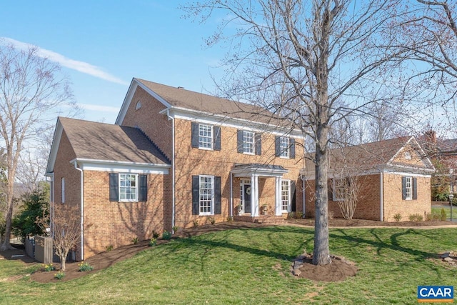 colonial inspired home featuring brick siding and a front lawn